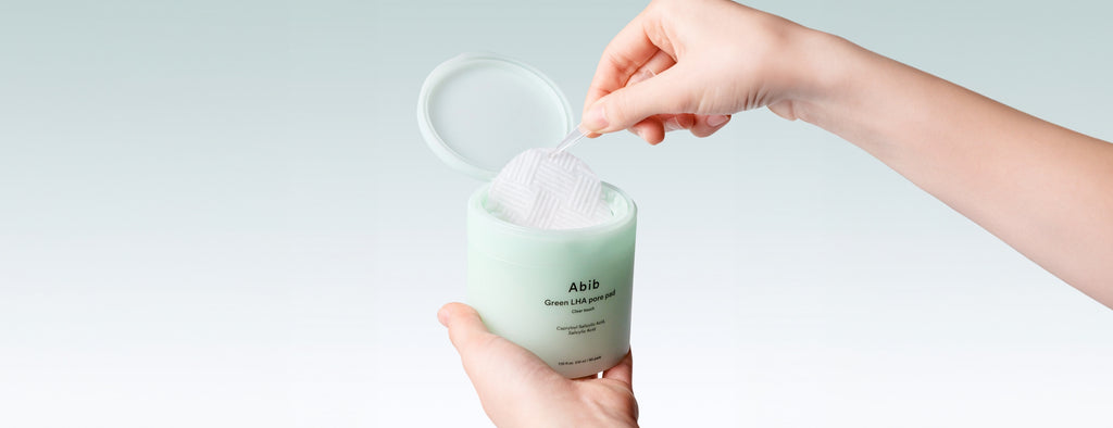 Abib Green LHA Pore Pad Clear Touch: tweezers lifting a pad from the jar