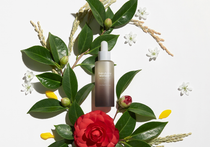 Haruharu Wonder Black Rice Facial Oil - 30ml — 30 ml dropper bottle among green leaves and red and white flowers.