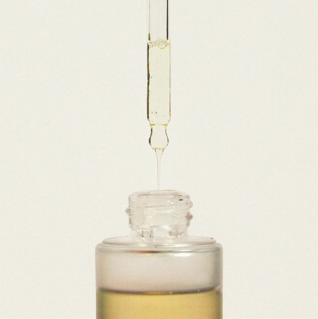 Haruharu Wonder Black Rice Facial Oil - 30ml — glass dropper releasing a drop of oil above the open 30 ml bottle.