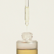 Haruharu Wonder Black Rice Facial Oil - 30ml — glass dropper releasing a drop of oil above the open 30 ml bottle.