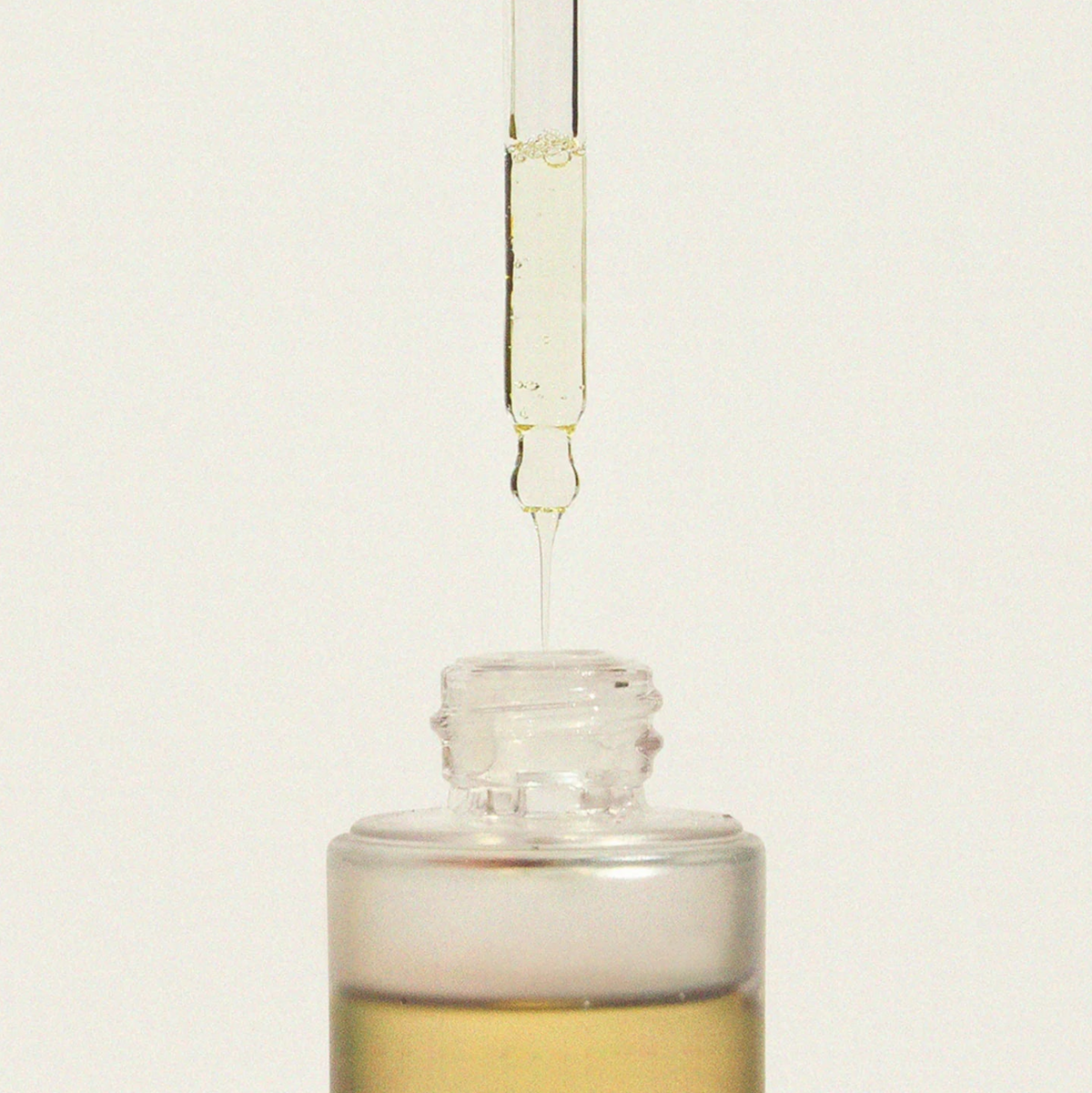 Haruharu Wonder Black Rice Facial Oil - 30ml — glass dropper releasing a drop of oil above the open 30 ml bottle.