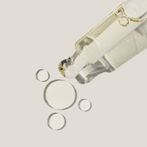 Haruharu Wonder Black Rice Facial Oil - 30ml — close-up of clear oil droplets beside the open bottle and dropper.