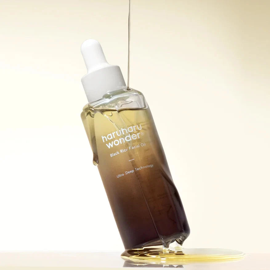 Haruharu Wonder Black Rice Facial Oil - 30ml — 30 ml bottle leaning in a pool of oil with a stream flowing from above.