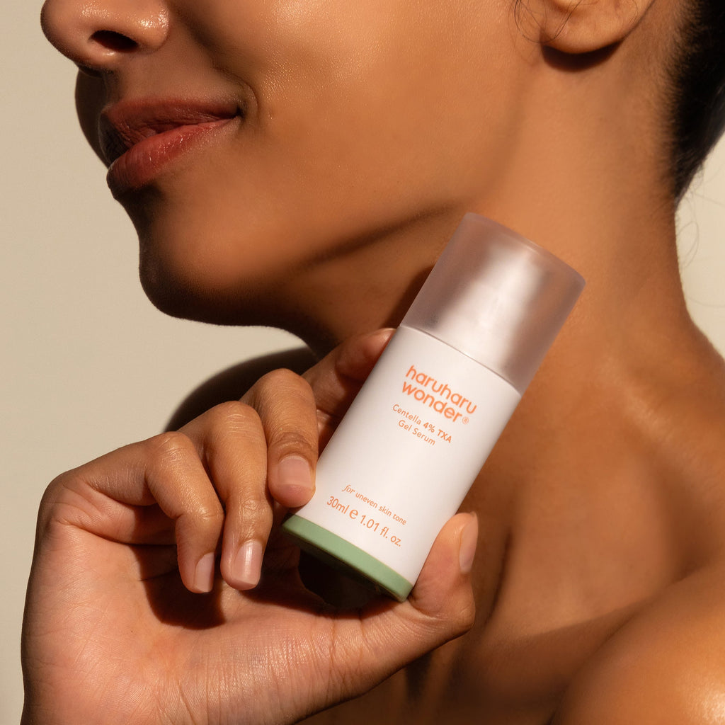 Haruharu Wonder Centella 4% TXA Gel Serum - 30ml — model holding the 30 ml TXA gel-serum bottle below her chin.