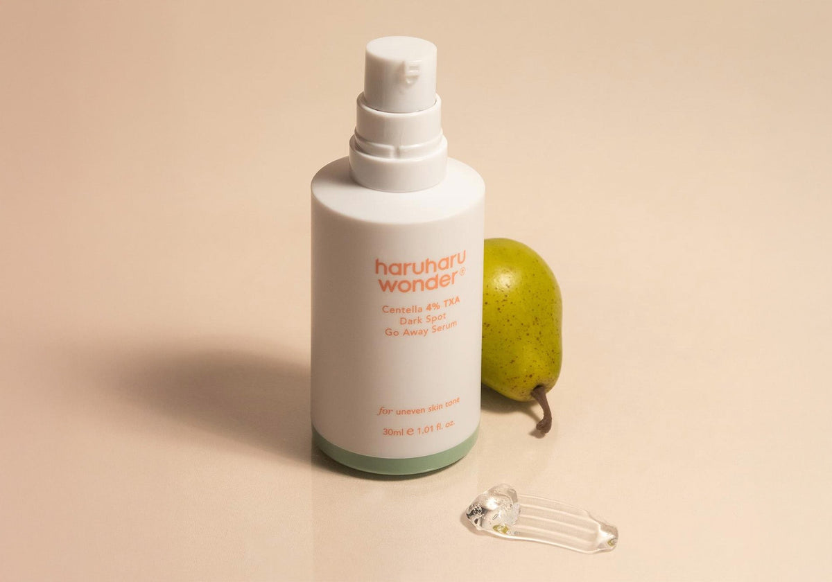 Haruharu Wonder Centella 4% TXA Gel Serum - 30ml — uncapped 30 ml TXA serum bottle with a pear and clear gel texture on a peach-coloured surface.