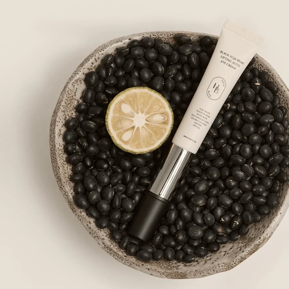 Heveblue Black Yuja Bean Lifting Auto Eye Cream — Eye cream product photographed with botanical props