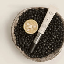 Heveblue Black Yuja Bean Lifting Auto Eye Cream — Eye cream product photographed with botanical props