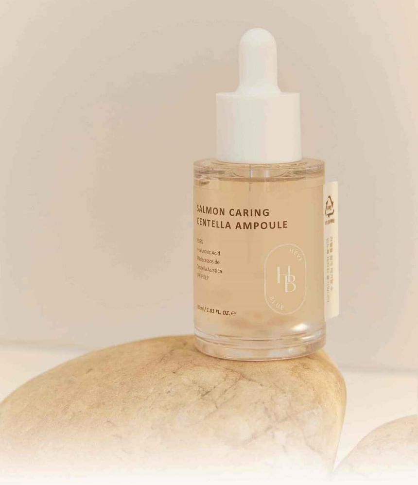 Heveblue Salmon Caring Centella Ampoule 30 ml — ampoule bottle on a textured pedestal.