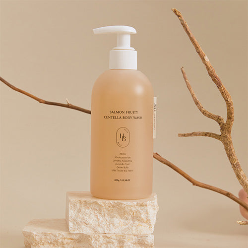 Heveblue Salmon Fruity Centella Body Wash — 300 g pump bottle displayed on a stone stand